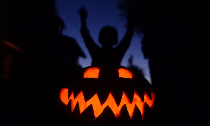 Children play behind a pumpkin carved and lit for Halloween in an undated file photo. (Frederic J. Brown/AFP/Getty Images)