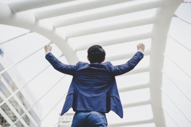 successfully young businessman keeping arms raised expressing positivity while standing outdoors 1150 3054