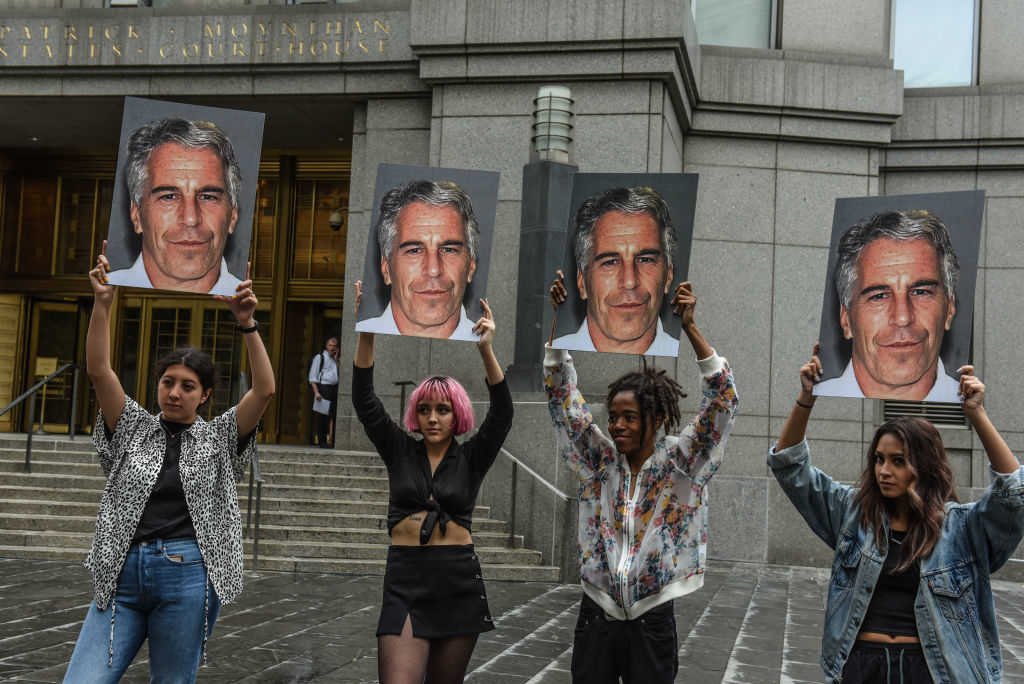 Một nhóm biểu tình có tên "Hot Mess" giơ bảng hiệu của Jeffrey Epstein trước tòa án Liên bang vào ngày 8 tháng 7 năm 2019 tại Thành phố New York. Theo báo cáo, Epstein sẽ bị buộc tội một tội buôn bán tình dục trẻ vị thành niên và một tội âm mưu tham gia buôn bán tình dục trẻ vị thành niên. (Ảnh của Stephanie Keith / Getty Images)