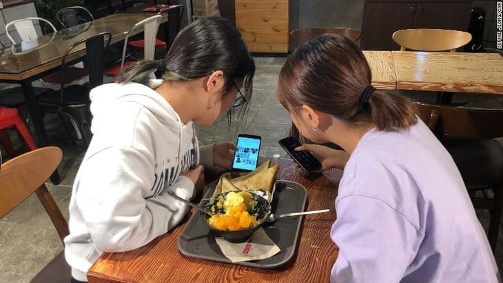 Hai nu sinh Han Quoc cham chu xem cach tao kieu toc moi tren smartphone trong mot quan ca phe o Seoul Anh chup man hinh CNN