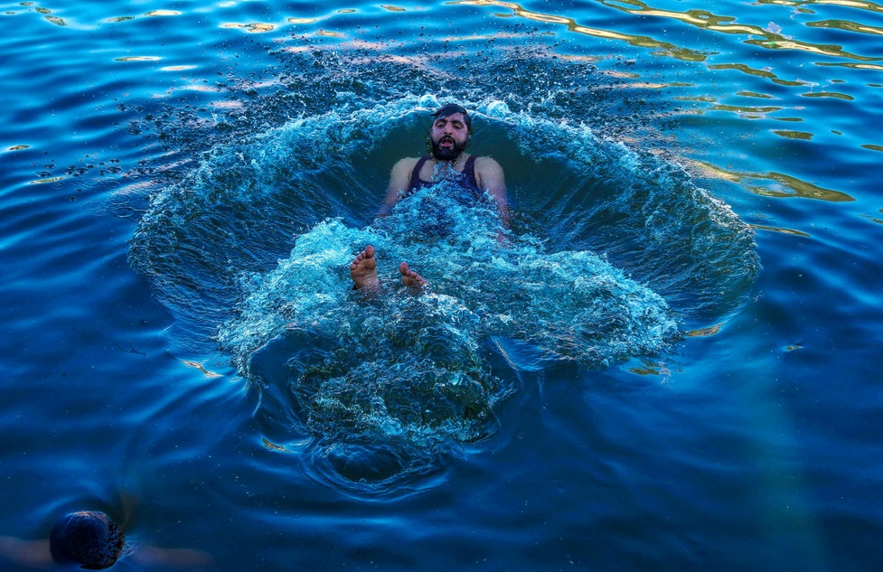 Một người đàn ông đầm mình trong hồ Dal ở Kashmir. Khu vực Himalaya cũng đang ghi nhận mức nhiệt độ trên mức bình thường trong mùa hè này. Ảnh: EPA